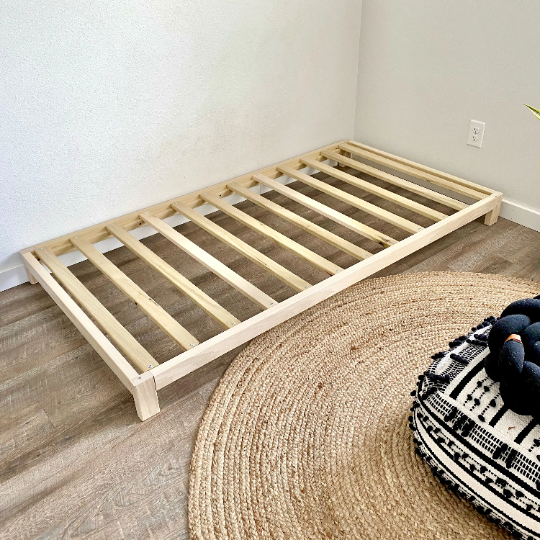 A solid wood platform bed, showcasing fine craftsmanship and minimalist design. The bed frame is constructed from high-quality wood with a smooth finish, offering a sturdy and stylish foundation for a comfortable night's sleep.