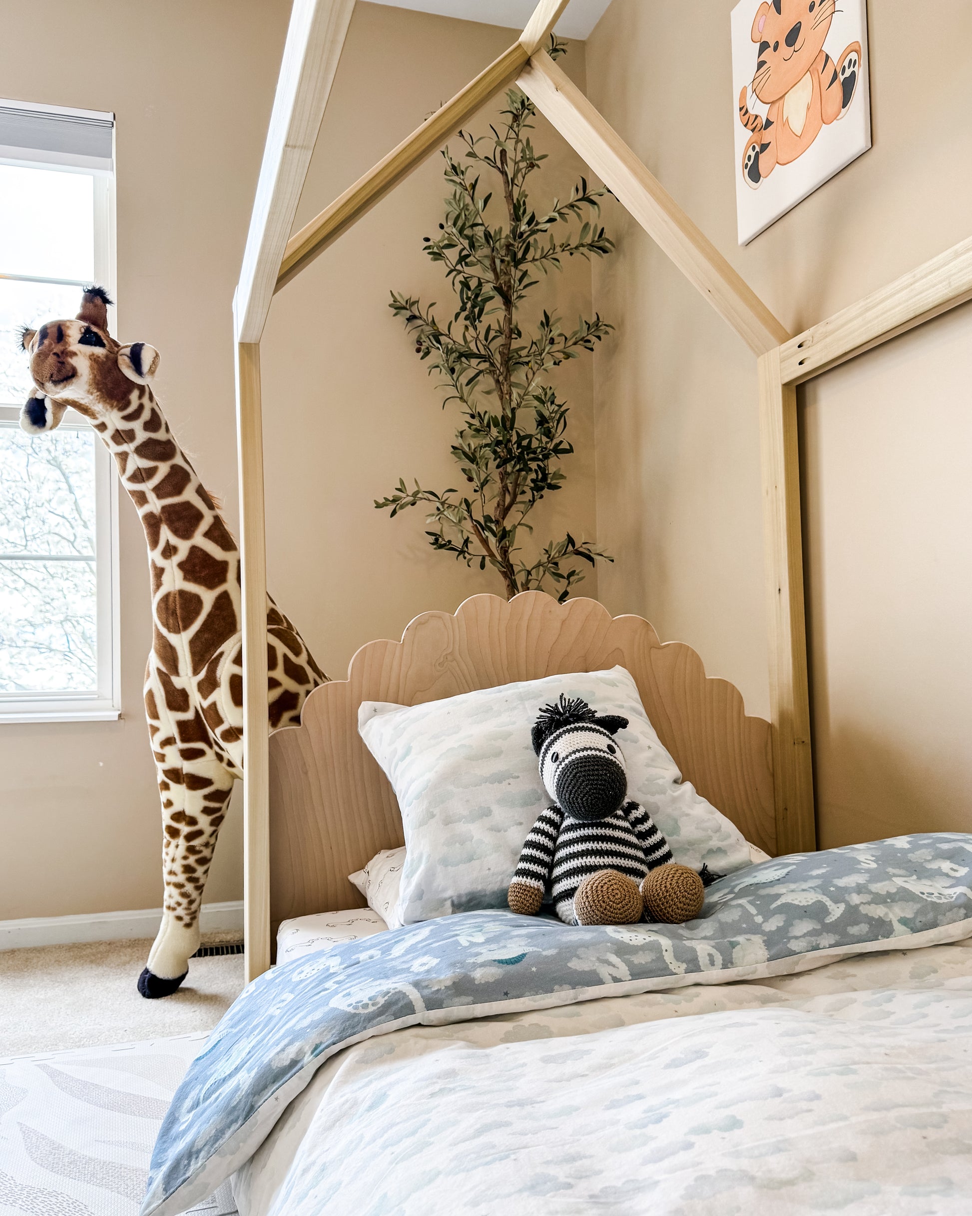 A cozy house-shaped children's bed made entirely of natural wood, featuring a headboard and footboard for added comfort and style. The bed resembles a quaint cottage. Crafted from sturdy wood, the frame provides stability and durability. Inside, a comfortable mattress with soft bedding invites children to rest and play. This wooden house bed with a headboard and footboard creates a cozy and inviting sleep space, perfect for fostering imagination and comfort in a child's bedroom.