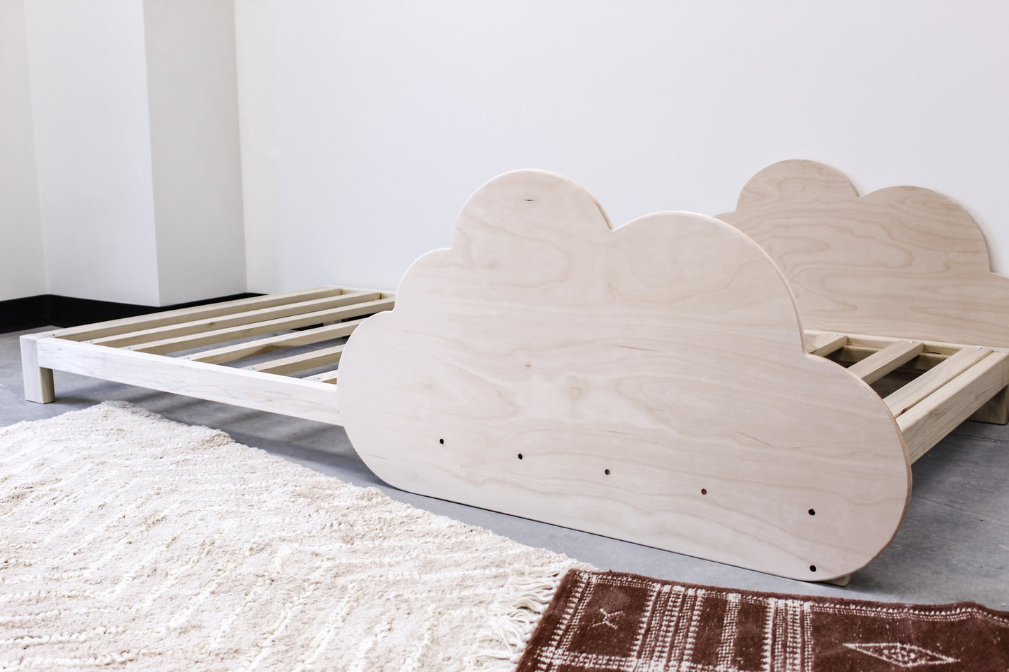 A solid wood platform bed featuring a minimalist design with a sleek, cloud-shaped railing. The bed frame is crafted from sturdy, natural wood with a smooth finish, providing a modern and elegant sleeping space.