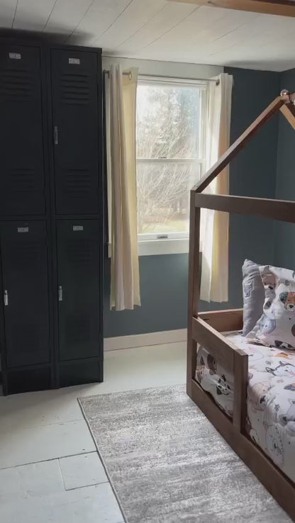 An adorable toddler bed with a low wooden frame, featuring safety rails on each side to prevent falls. The bed is adorned with colorful cartoon-themed bedding, including pillows and a soft blanket. Placed in a cozy bedroom corner with stuffed animals scattered around, creating a warm and inviting atmosphere for a young child's sleep space.