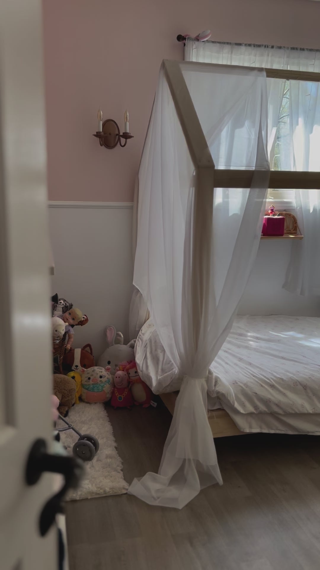 A charming house-shaped children's bed crafted entirely from natural wood, featuring a cozy and inviting design. The bed resembles a miniature house, complete with a peaked roof, window cutouts, and a sturdy wooden frame. Inside, a comfortable mattress is adorned with soft bedding, providing a cozy spot for children to sleep and play. With safety rails along the sides for added security, this wooden house bed creates a whimsical and imaginative sleep space for young ones to enjoy in their bedroom.